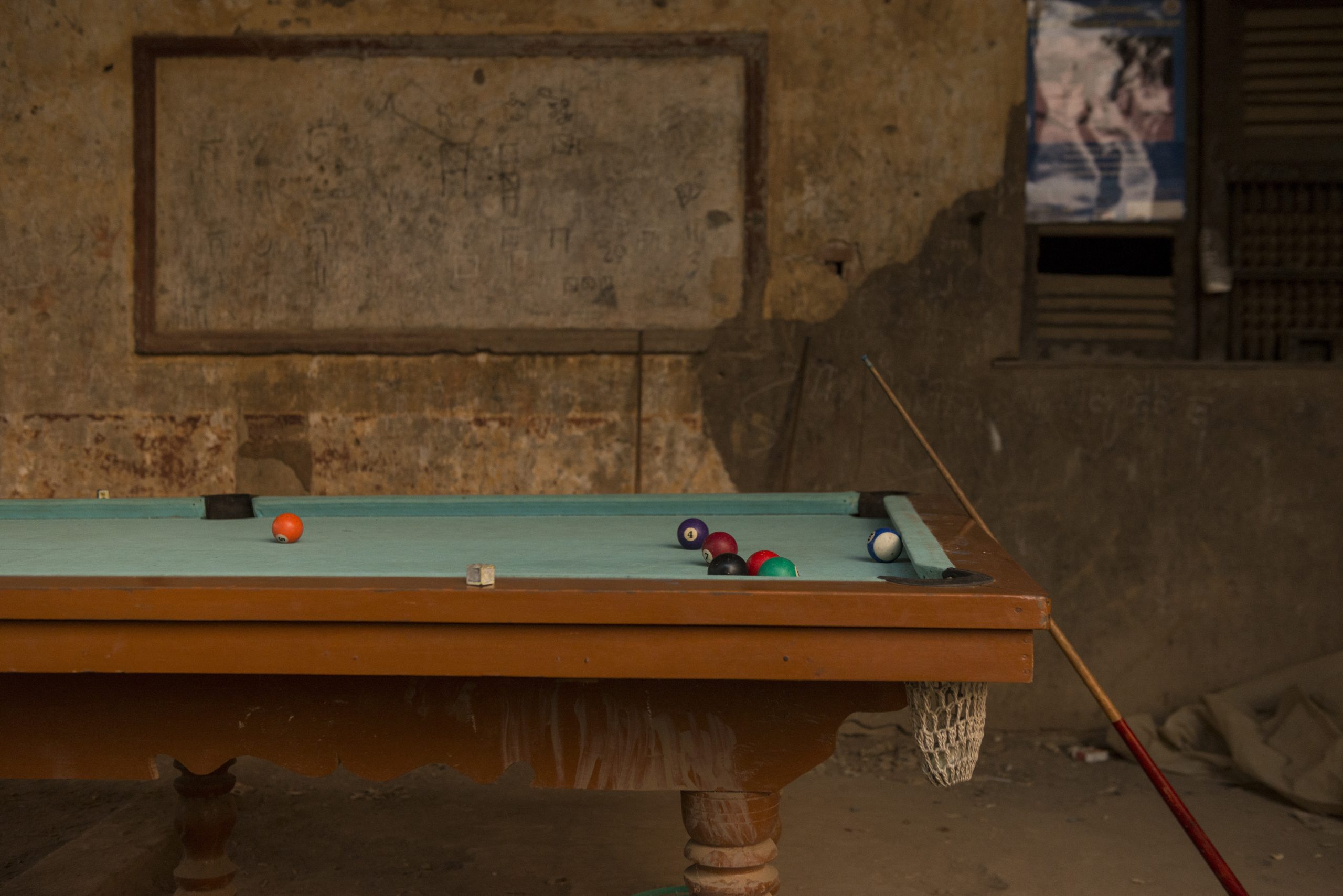 A solitary pool table awaits its next players in a rustic setting