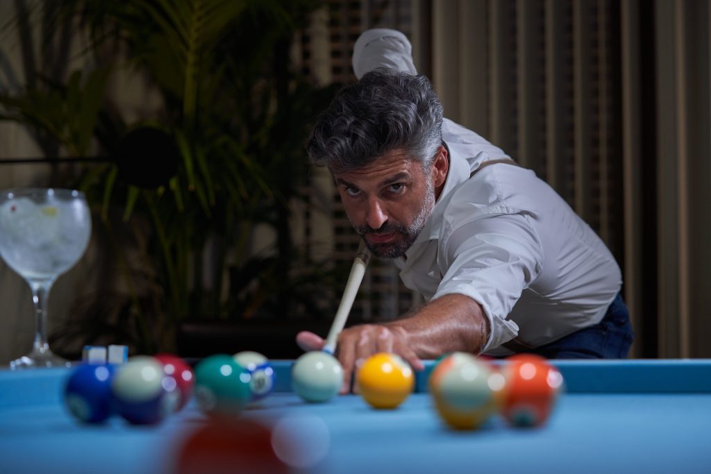Man Playing Pool Inside Elegant Home at Night