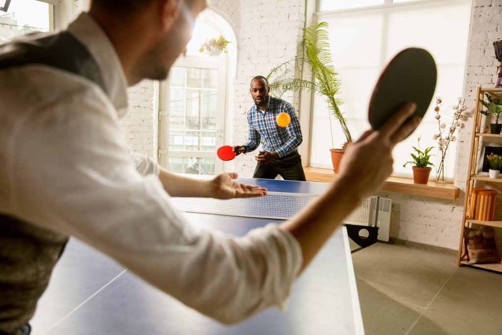 Men Playing Table Tennis in a Bright Room