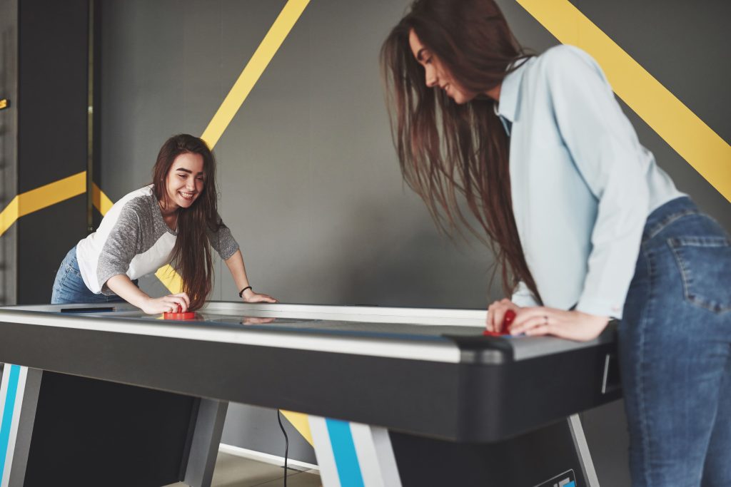 Young Women Playing Air Hockey Indoors