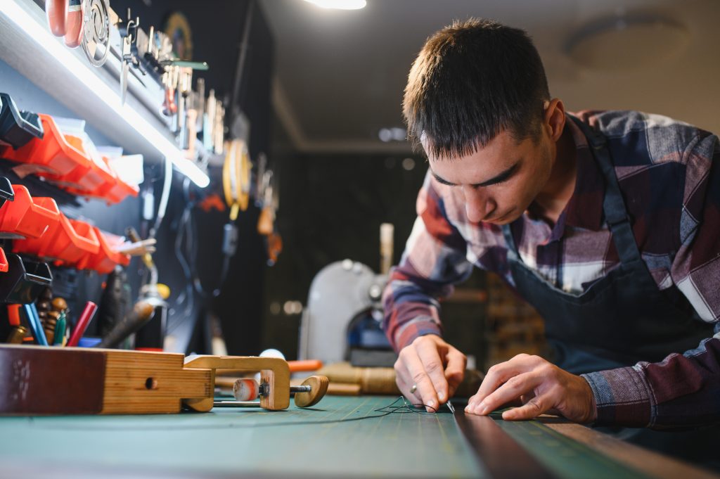 leather craftsman is carefully to make a leather product for a customer