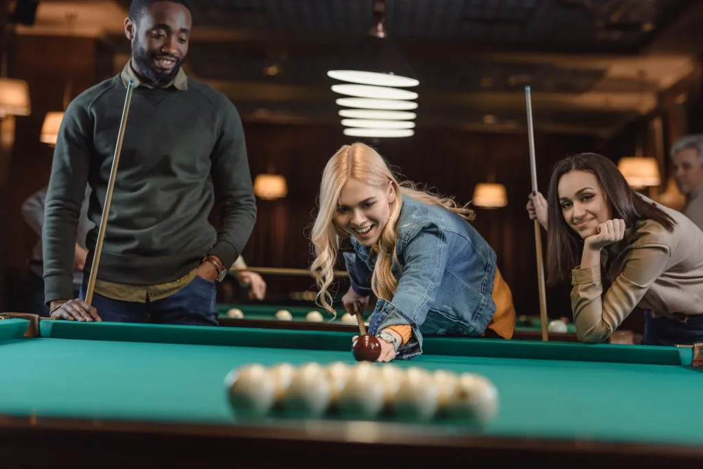 young multiethnic friends playing in pool at bar
