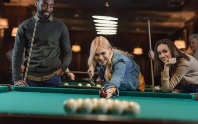 young multiethnic friends playing in pool at bar